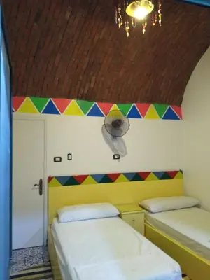 a room with two beds and a colorful wall at Meshra Katto in Aswan