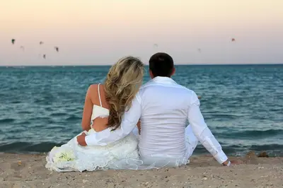 a bride and groom sitting on the beach at Apartments Desert rose near the sea RedSeaLine in Hurghada