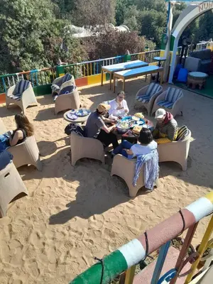a group of people sitting around a table in the sand at El Prince Guesthouse in Aswan