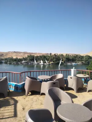 a row of tables and chairs on a balcony overlooking a river at El Prince Guesthouse in Aswan