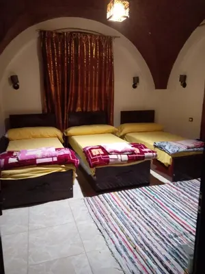 a room with three beds and a rug at El Prince Guesthouse in Aswan