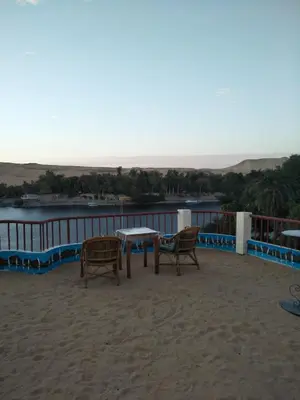a table and chairs on a balcony with a view of the water at El Prince Guesthouse in Aswan