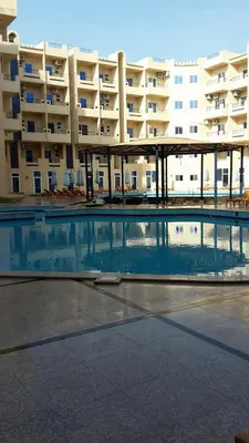 an empty swimming pool in front of a large apartment building at Tiba Resort AA in Hurghada