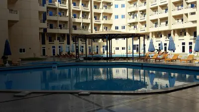 a swimming pool in front of a large building at Tiba Resort AA in Hurghada