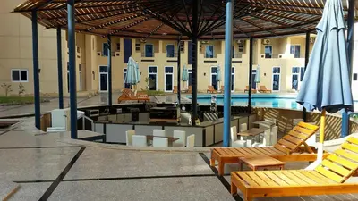 a patio with chairs and an umbrella and a pool at Tiba Resort AA in Hurghada