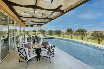a patio with a table and chairs next to a swimming pool at Steigenberger Makadi - Adults Friendly 16 Years Plus in Hurghada