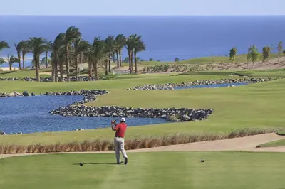 a man standing on a golf course next to a lake at Steigenberger Makadi - Adults Friendly 16 Years Plus in Hurghada