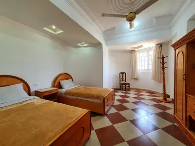 a bedroom with two beds and a checkered floor at Spring Hotel Luxor in Luxor
