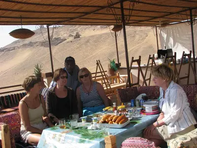 a group of people sitting around a table in the desert at Bet El Kerem Guesthouse in Aswan