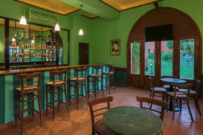 a green room with a bar with chairs and tables at JAZ Makadi Saraya Resort in Hurghada