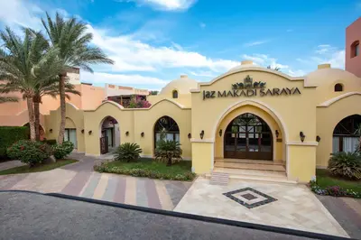 a large yellow building with palm trees in front of it at JAZ Makadi Saraya Resort in Hurghada