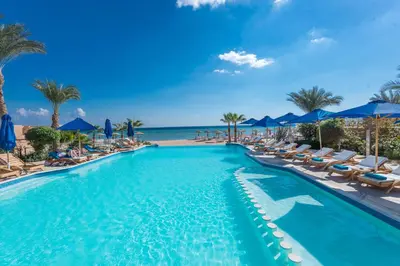 a pool with chairs and the ocean in the background at Shams Prestige Abu Soma (Adults Only) in Hurghada