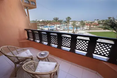 a balcony with two chairs and a view of a pool at Calimera Blend Paradise in Hurghada