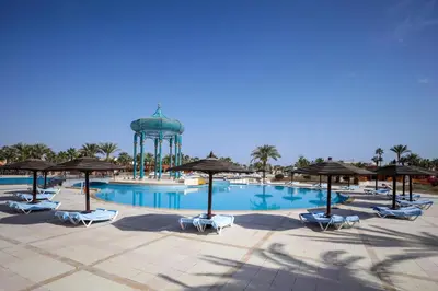 a pool with chairs and a water tower in the background at Calimera Blend Paradise in Hurghada
