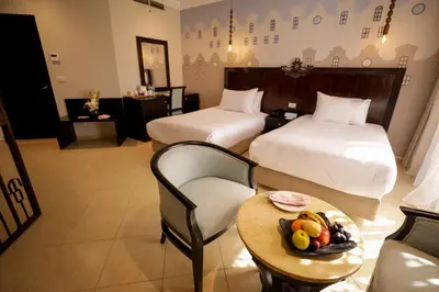 a hotel room with two beds and a table with a bowl of fruit at Calimera Blend Paradise in Hurghada