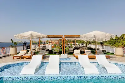 a pool on the roof of a hotel with chairs and umbrellas at Tamr Nile Cruise - 04 Nights Every Monday from Luxor - 03 Nights Every Friday from Aswan in Luxor