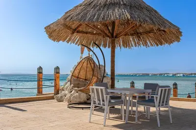 a table and chairs under a straw umbrella on the beach at Siva Grand Beach in Hurghada