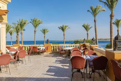 a patio with tables and chairs and palm trees at Grand Waterworld Makadi - Couples and Families Only in Hurghada