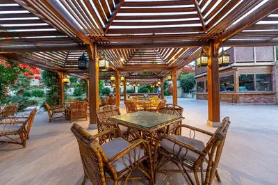 a patio with a table and chairs and a wooden ceiling at Makadi Palace - Couples and Families Only in Hurghada