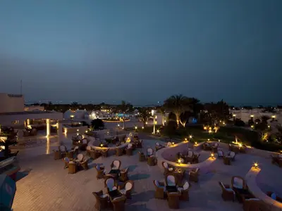 a patio with chairs and tables at night at Hurghada Coral Beach Hotel in Hurghada