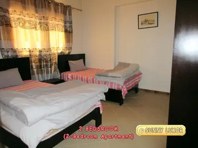 two beds sitting in a room with curtains at Sunny Luxor in Luxor