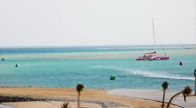 a red boat in the water near a beach at New Marina MP 37 in Hurghada