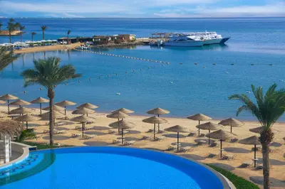 a view of a beach with umbrellas and a cruise ship at JAZ Elite Casa Del Mar Beach in Hurghada