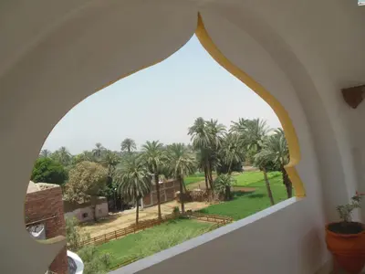 an arched window with a view of palm trees at Cleopatra Hotel Luxor in Luxor