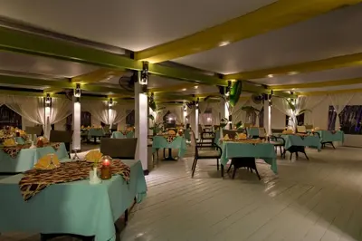 a dining room with green tables and chairs at Hilton Marsa Alam Nubian Resort in Abu Dabab