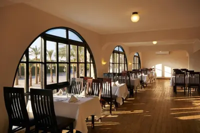 a dining room with tables and chairs and windows at Giftun Azur Resort in Hurghada