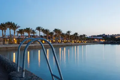 a pool of water with palm trees and lights at Arabia Azur Resort in Hurghada