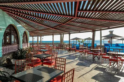 a patio with tables and chairs with the ocean in the background at Arabia Azur Resort in Hurghada
