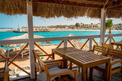 a table and chairs on a beach with the water at JAZ Palmariva Beach in Hurghada