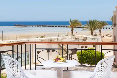 a table and chairs on a balcony with a beach at JAZ Palmariva Beach in Hurghada