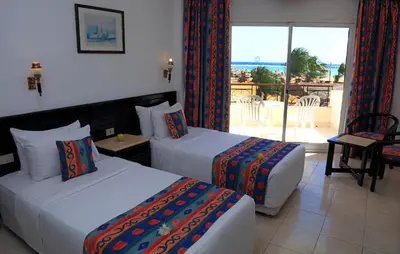 a hotel room with two beds and a balcony at JAZ Palmariva Beach in Hurghada