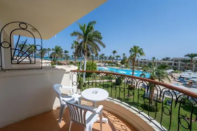 a balcony with a table and chairs and a pool at JAZ Royal Palmariva in Hurghada