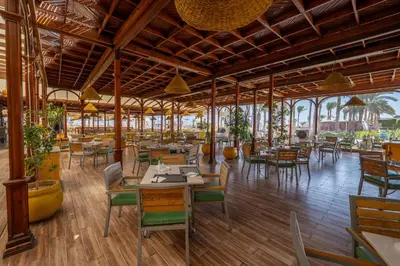 a restaurant with wooden floors and tables and chairs at JAZ Royal Palmariva in Hurghada