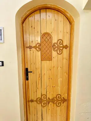 a wooden door with a handle on a wall at Queen House in Aswan