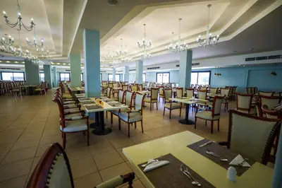 a dining room with tables and chairs and chandeliers at Blend Club Aqua Resort in Hurghada