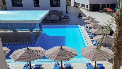 a swimming pool with umbrellas and a group of chairs and tables at Blend Club Aqua Resort in Hurghada