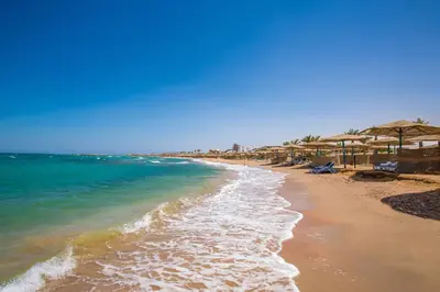 a sandy beach with umbrellas and the ocean at Blend Club Aqua Resort in Hurghada
