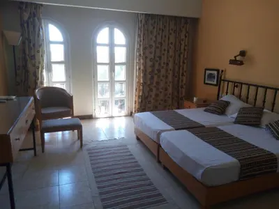 a bedroom with two beds and a desk and two windows at EL Gouna Abu tig marina studio- economy stay in Hurghada