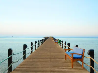 a wooden pier with a row of chairs on the water at Stella Beach Resort & Spa, Makadi Bay in Hurghada