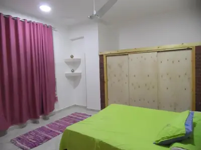 a bedroom with a green bed and a red curtain at Nour House in Luxor