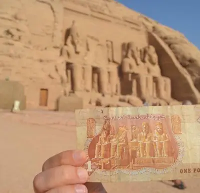 a person holding a piece of money in front of thearaoh at david hostel in Aswan