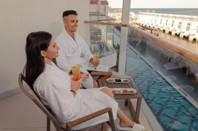 a man and woman sitting on a balcony with drinks at Bellagio Beach Resort & Spa in Hurghada