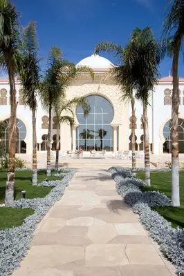 a walkway in front of a building with palm trees at Old Palace Resort Sahl Hasheesh in Hurghada