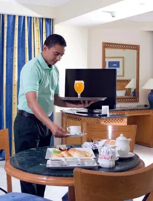 a man standing in front of a table with a tray of food at Old Palace Resort Sahl Hasheesh in Hurghada