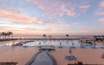 a swimming pool with chairs and umbrellas on a beach at Old Palace Resort Sahl Hasheesh in Hurghada