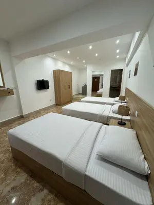 a hotel room with three beds and a television at Lilly Rooms and Studio in Hurghada